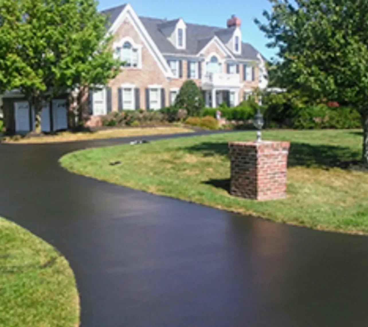 Professional asphalt seal coating application on residential driveway