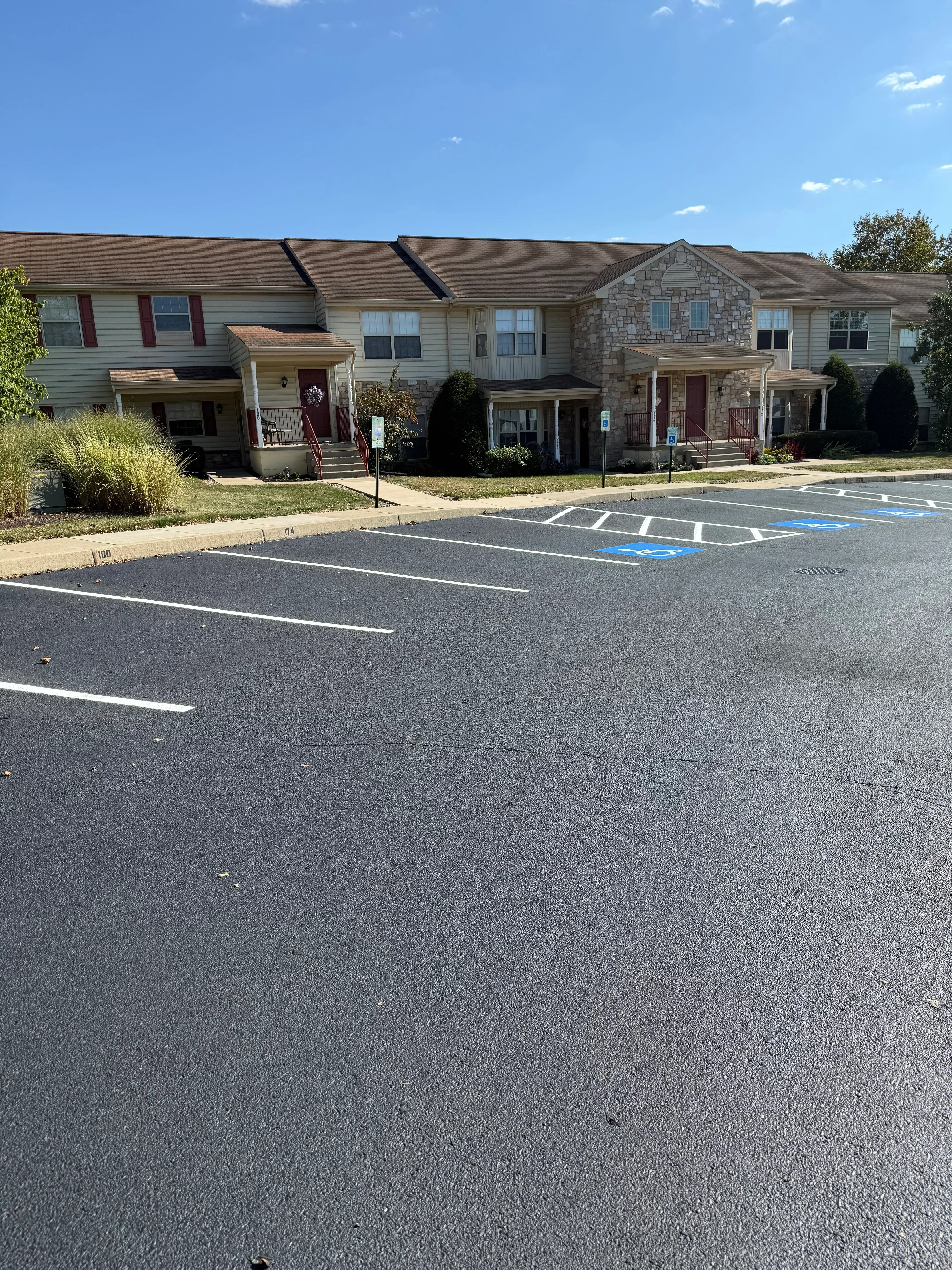 Newly paved asphalt driveway with white line markings next to residential building