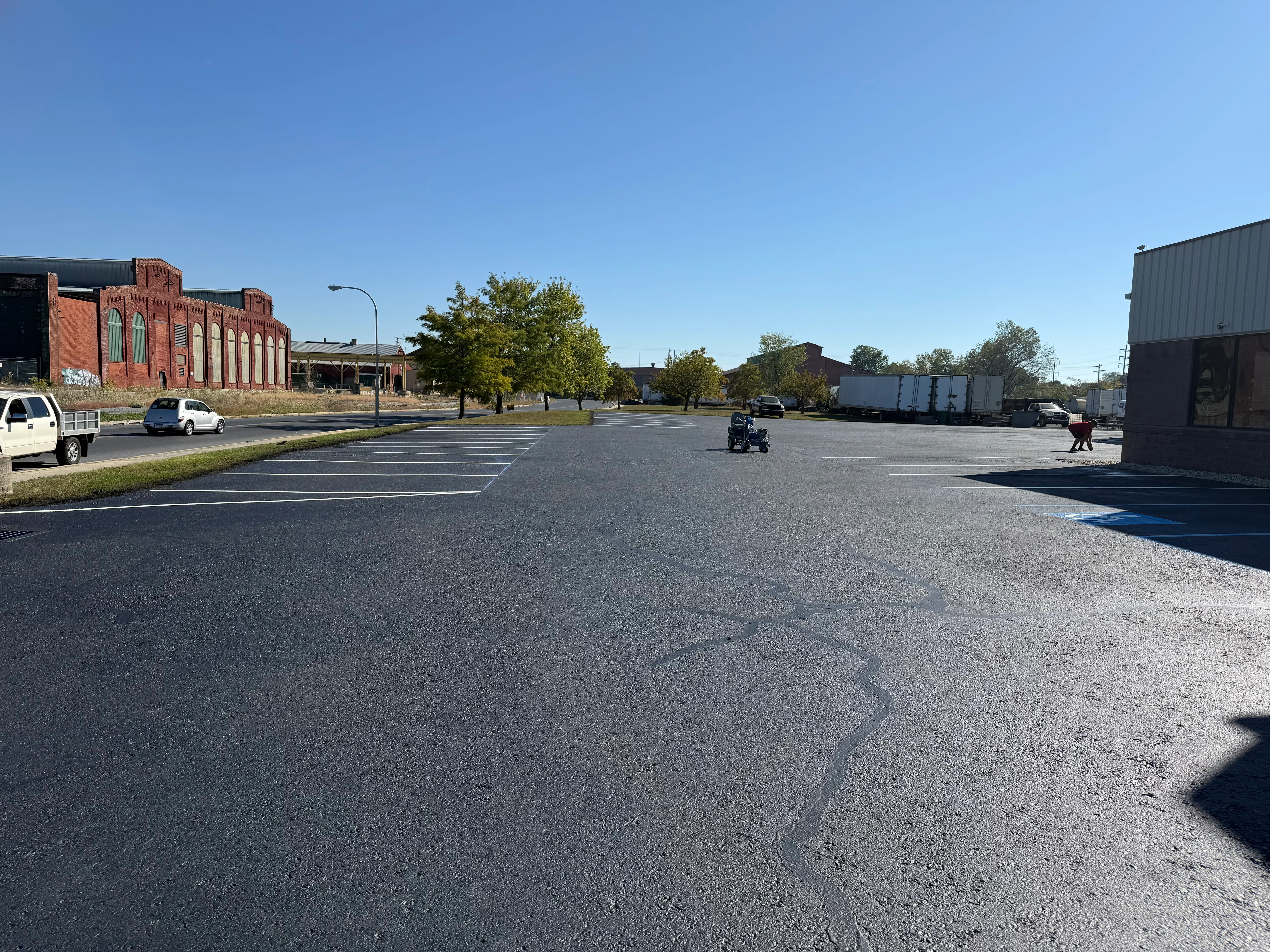 Newly paved asphalt parking lot with white parking space lines and directional markings
