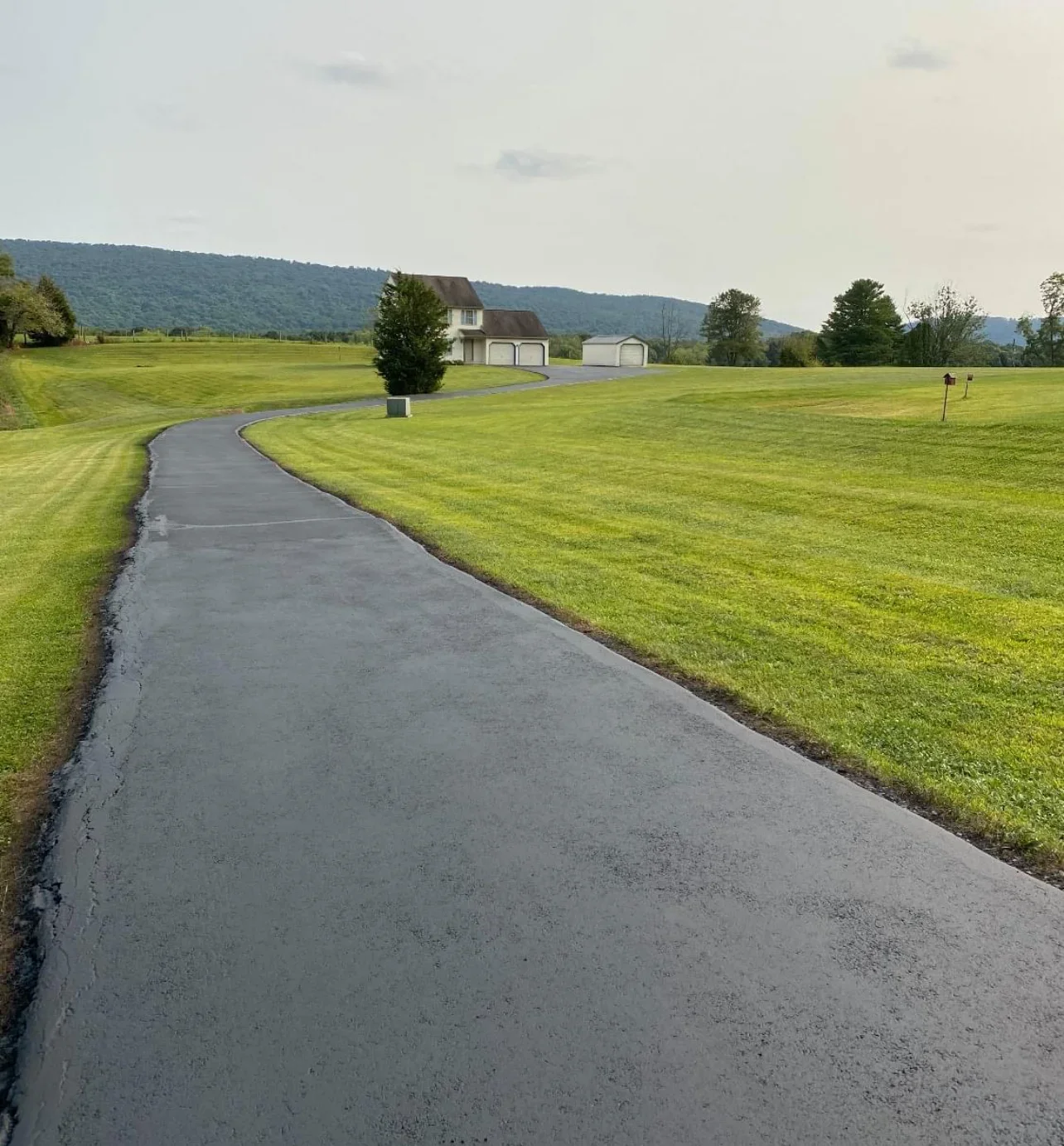 Curved asphalt driveway with clean edges on rural residential property