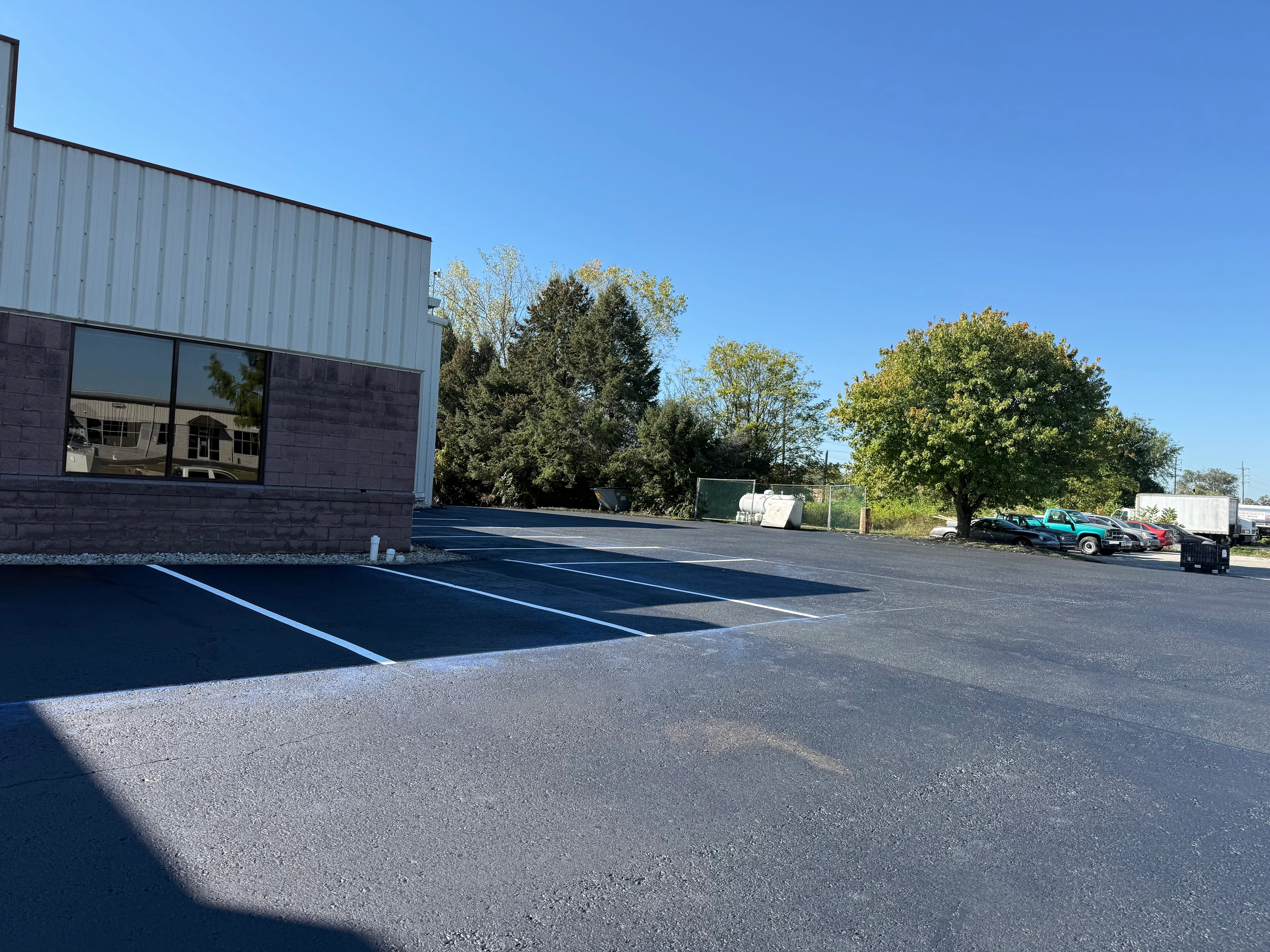 Sealed asphalt parking lot with fresh blue line striping and industrial building