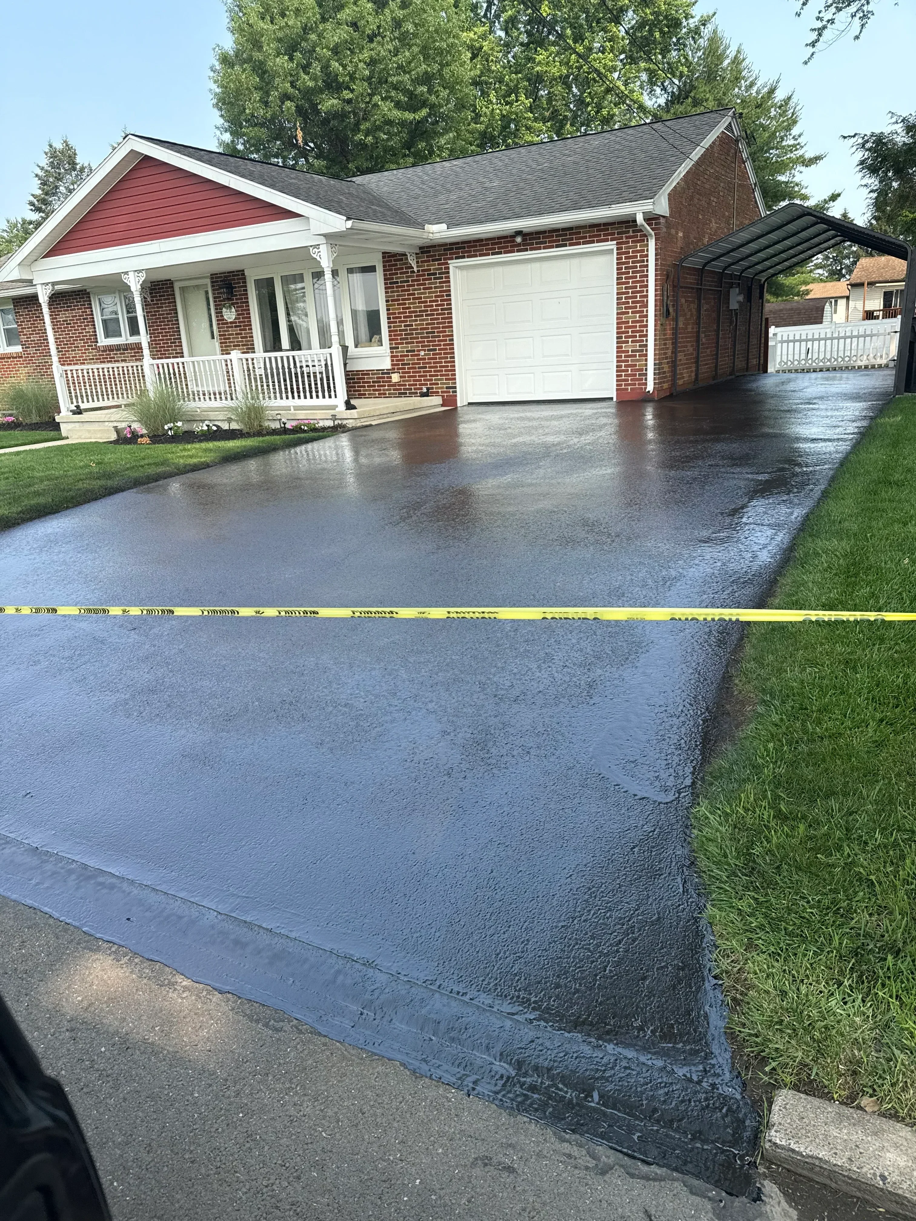 Newly sealed asphalt driveway with dark protective coating applied to residential property