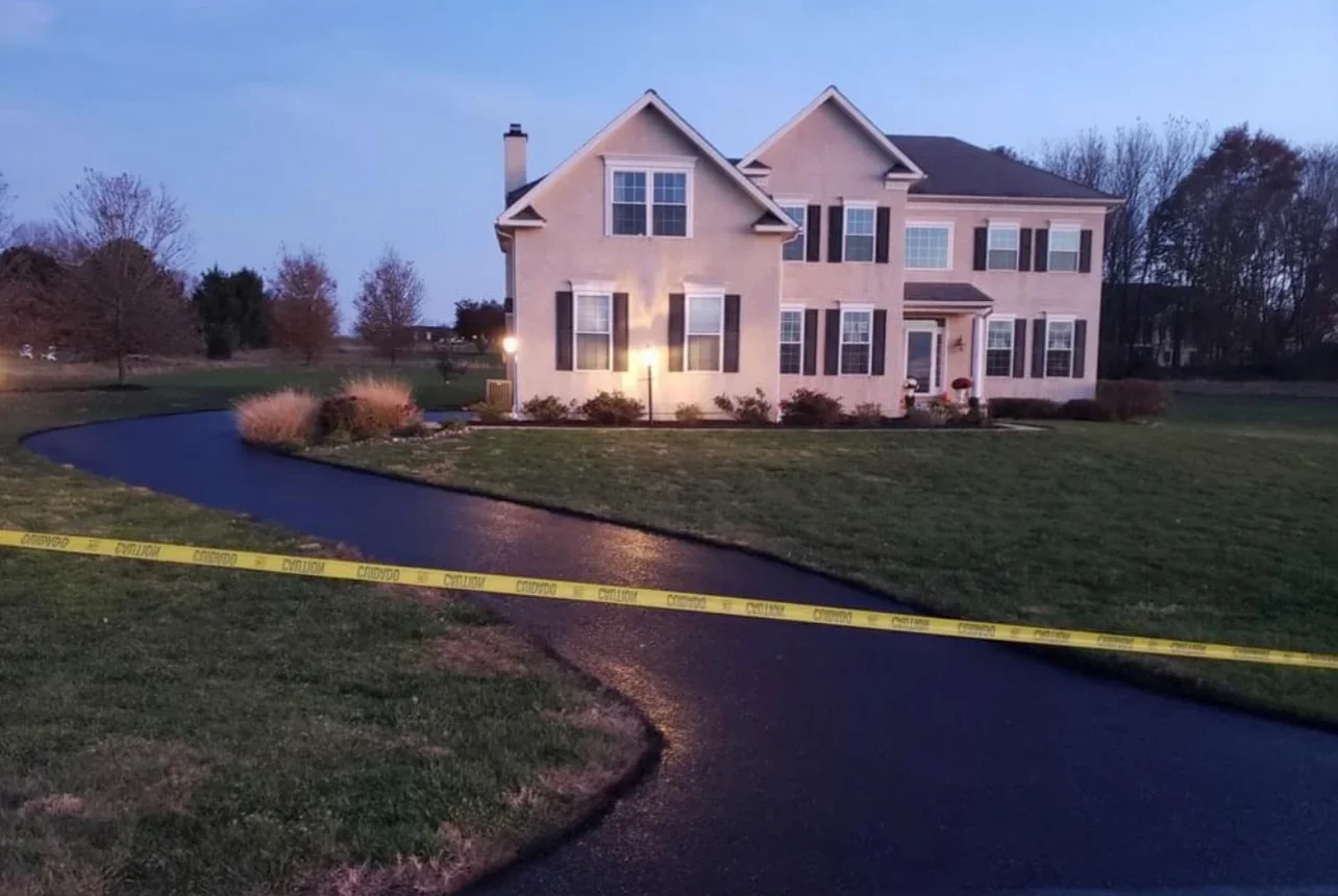 Sealed asphalt driveway with dark finish in front of pink colonial home at dusk