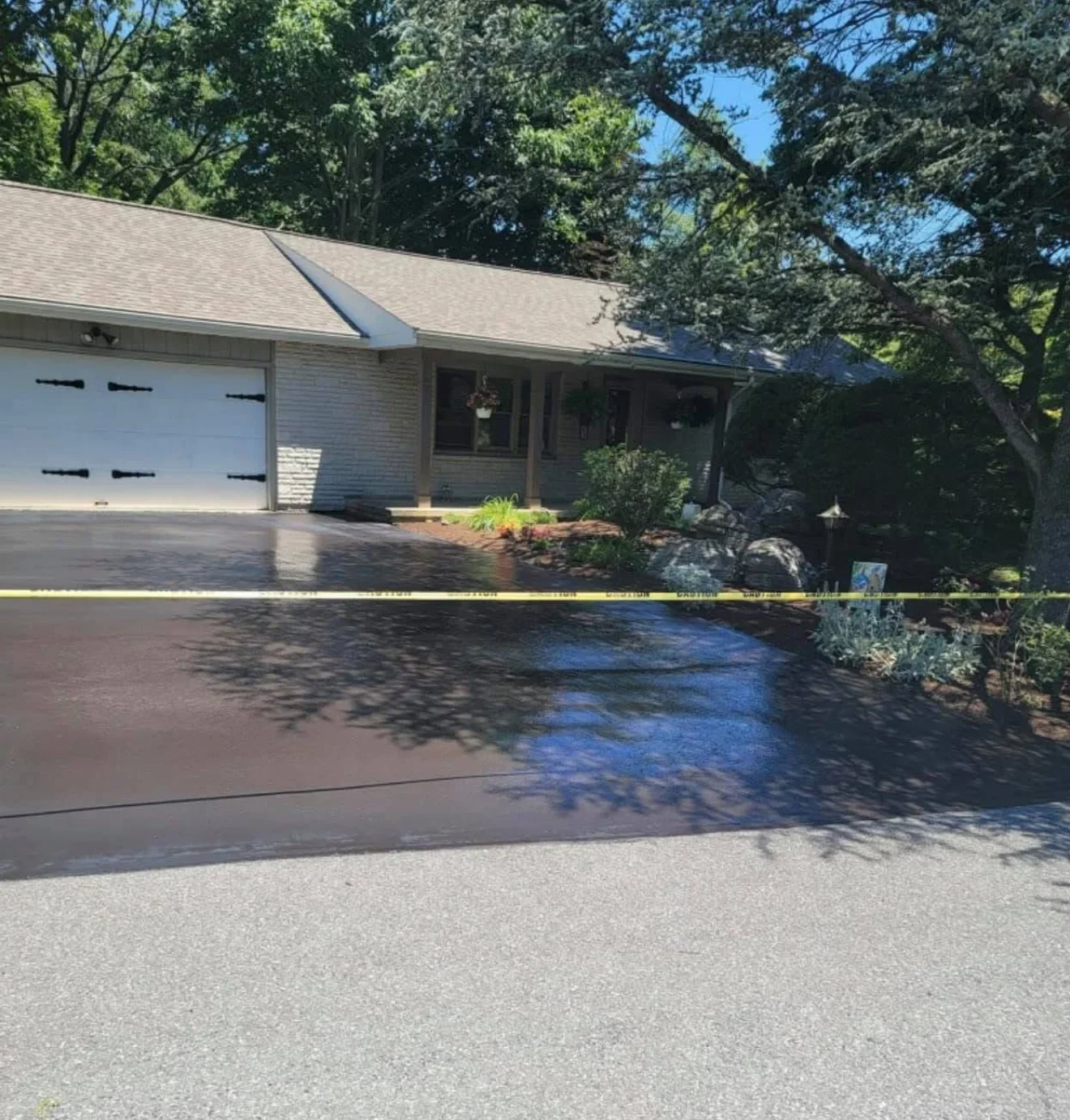 Sealed asphalt driveway with crack repair and fresh dark finish in front of residential home