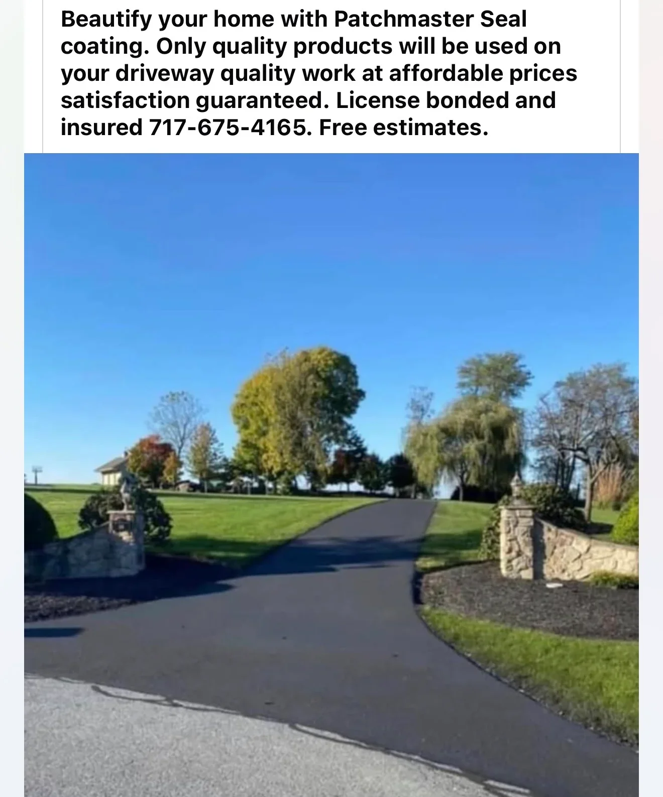 Freshly sealed asphalt driveway with dark finish and curved design bordered by stone pillars