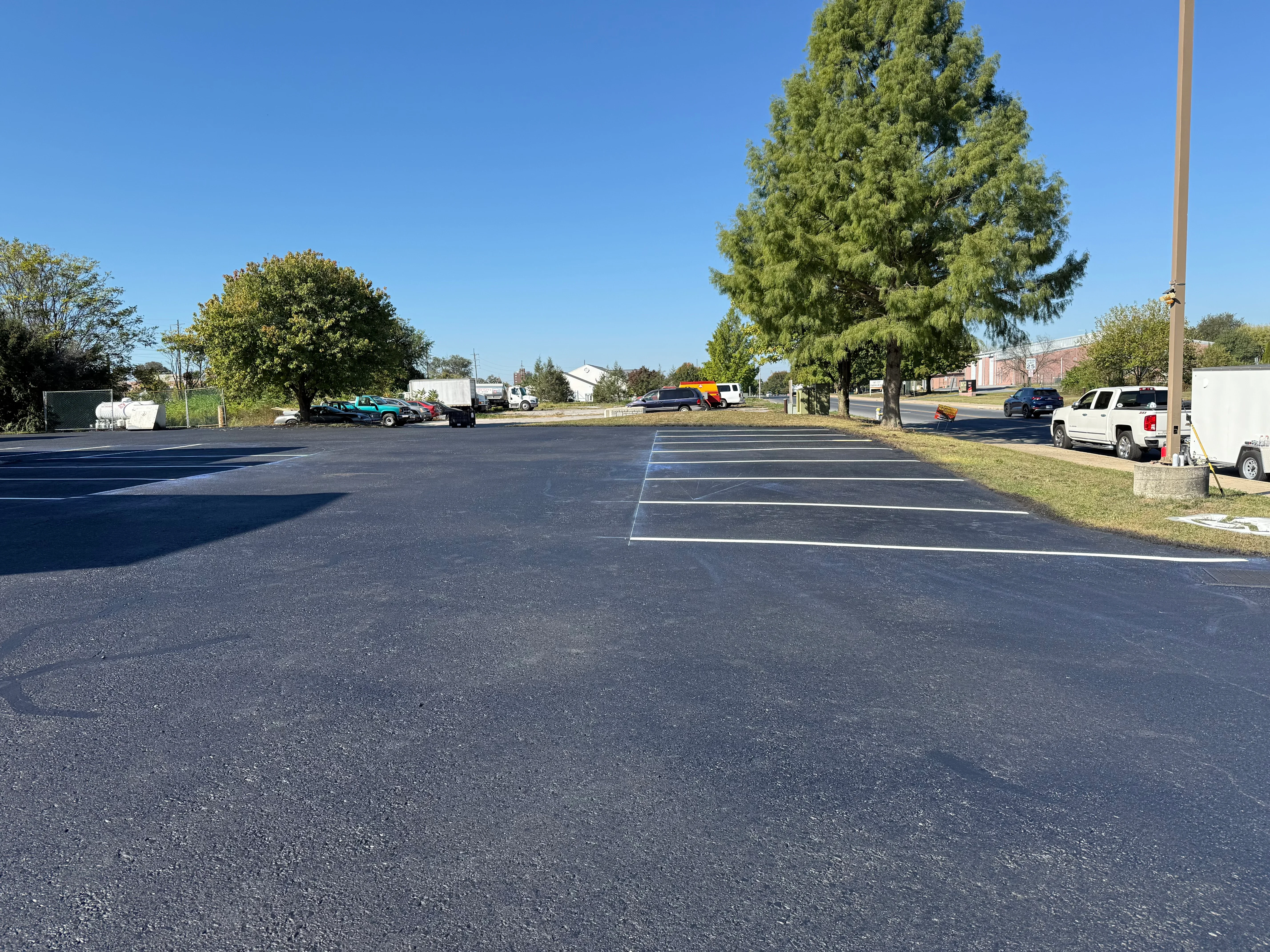 Newly sealed asphalt parking lot with white parking space lines and directional markings