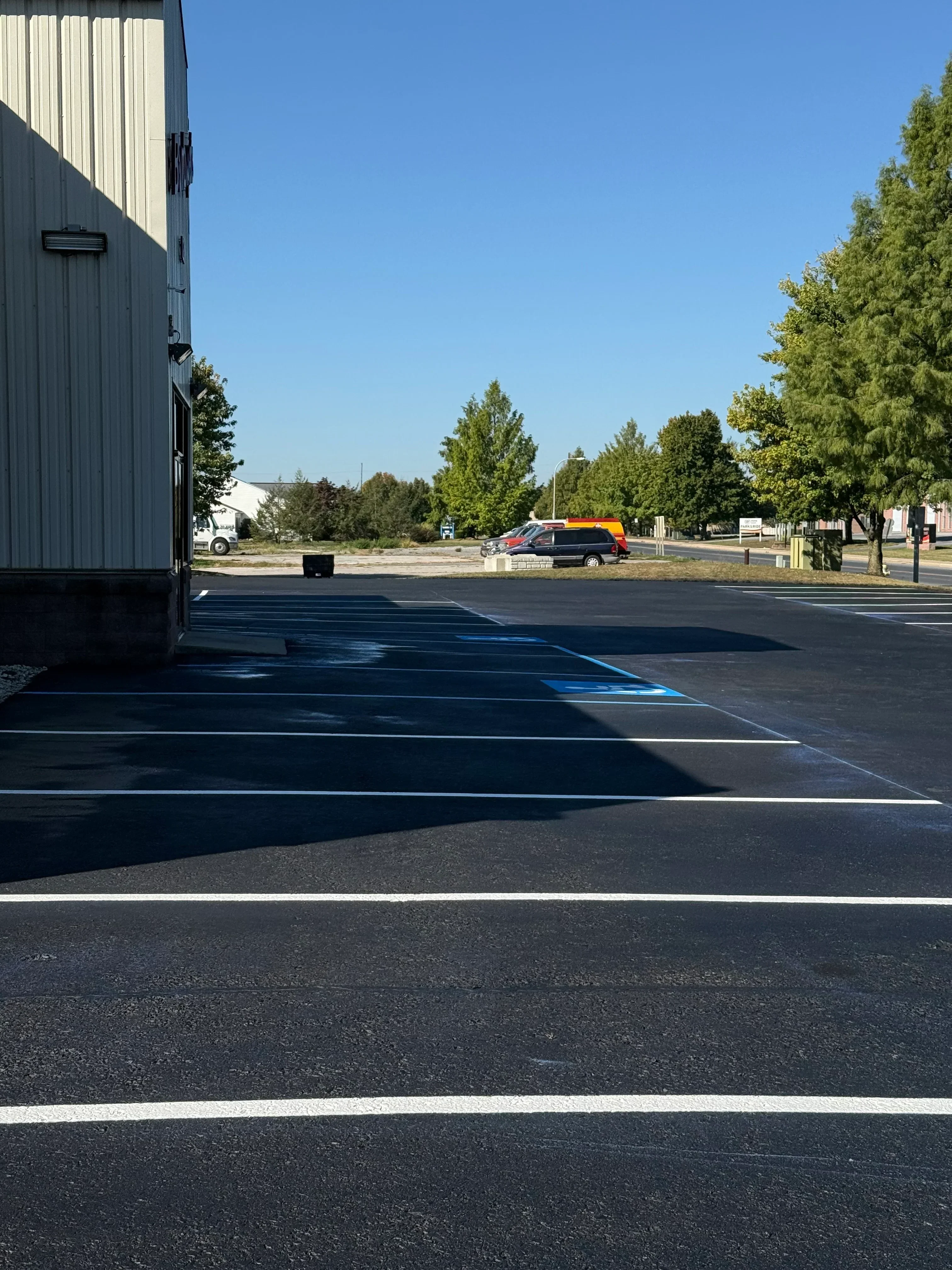 Sealed asphalt driveway with white stripe markings and fresh sealcoat finish