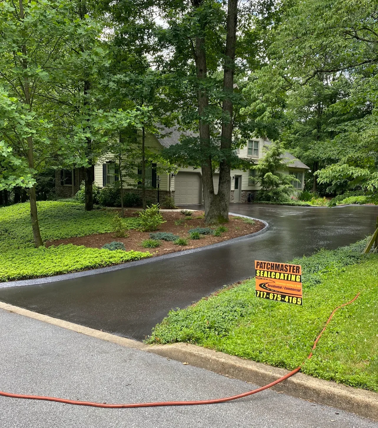 Newly sealed asphalt driveway with curved design and concrete edge borders