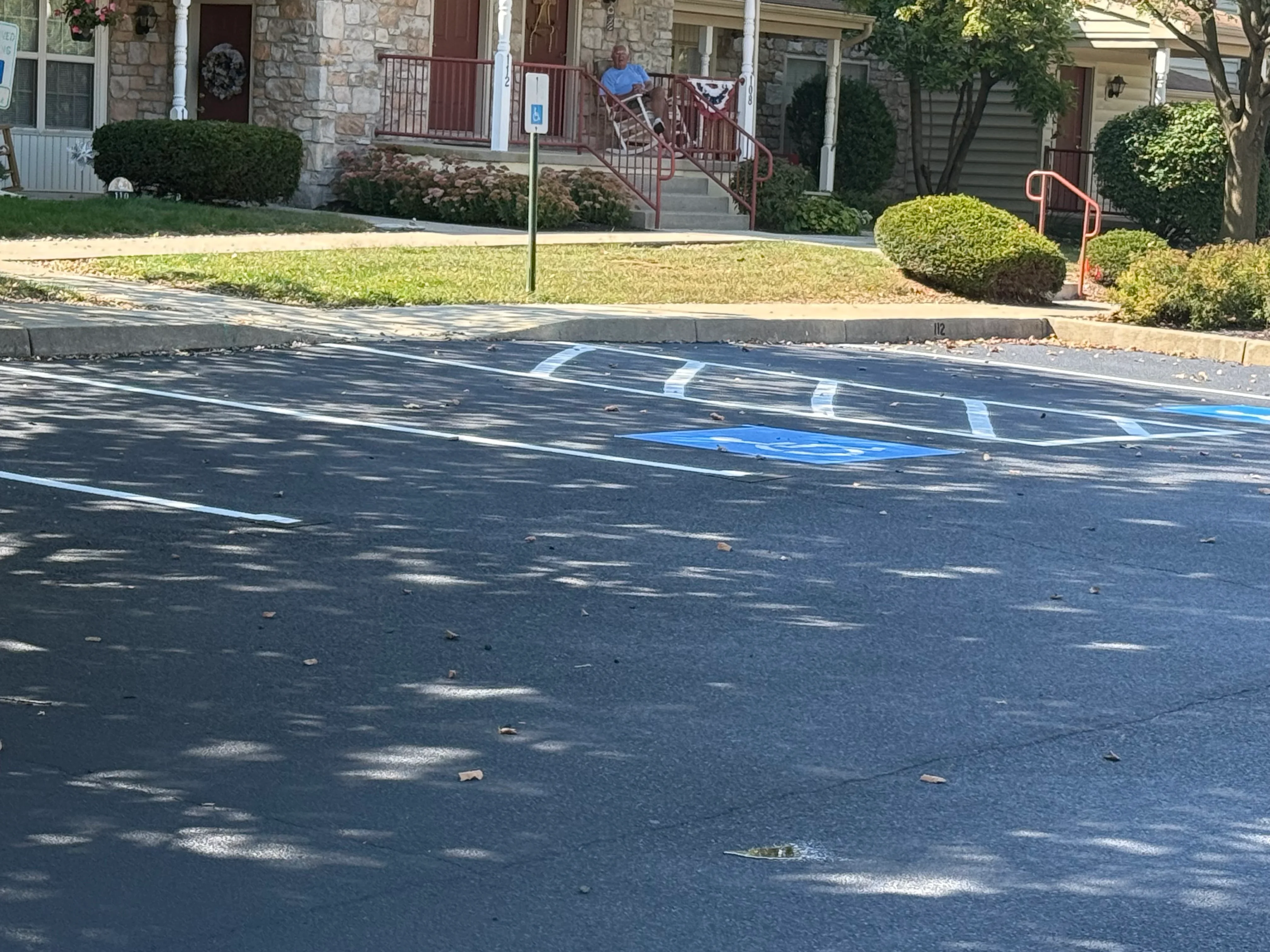 Freshly sealed asphalt with white striping and blue handicap parking space marking