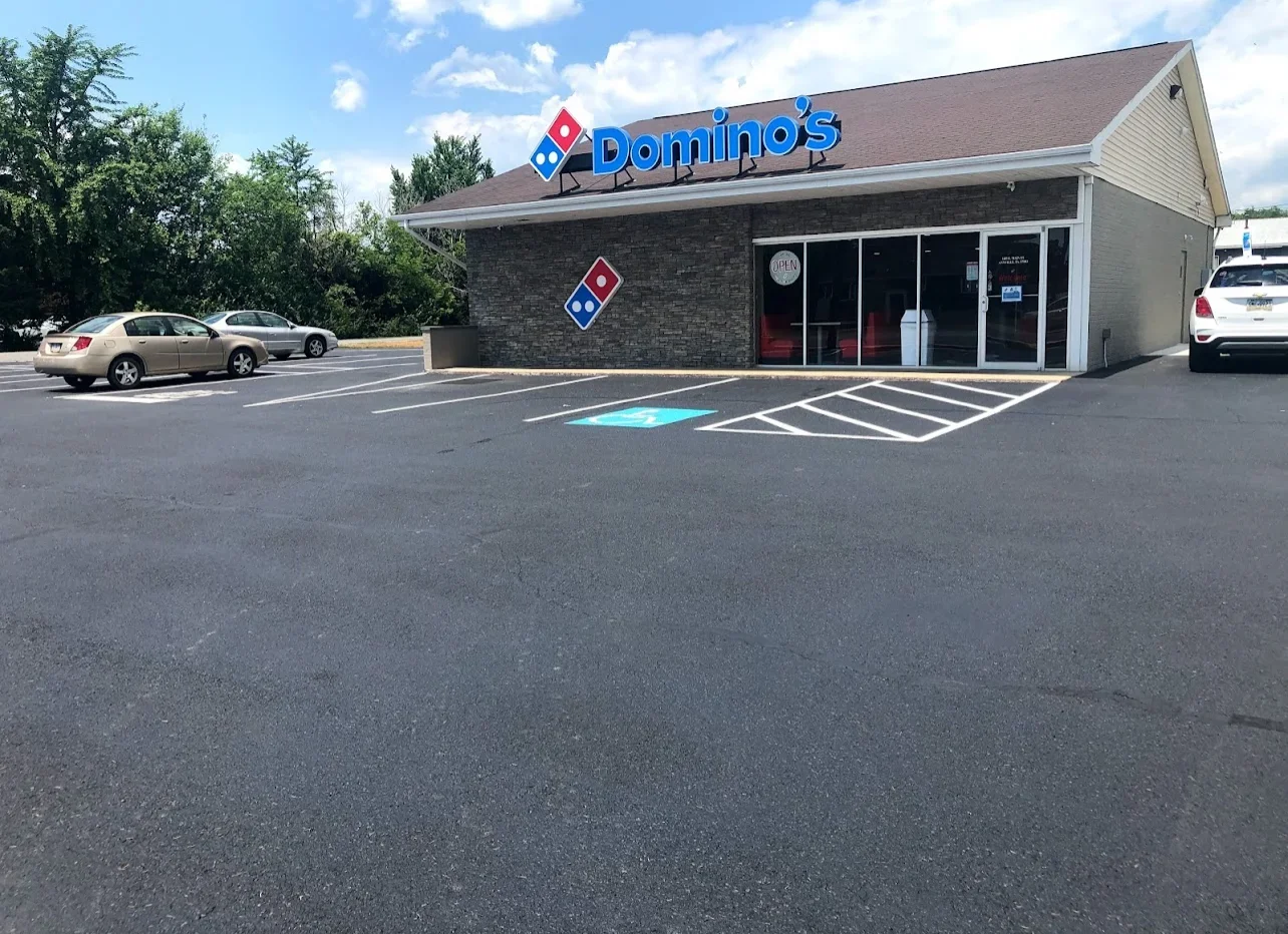Sealed asphalt parking lot with white striped spaces and blue accessible parking spot