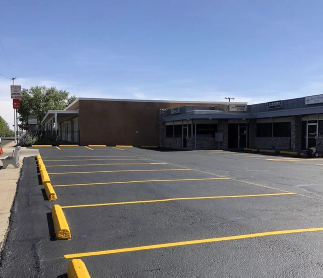 Newly sealed asphalt parking lot with bright yellow parking space lines and curb markings
